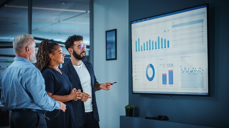 Business Meeting with three people reviewing a BI dashboard