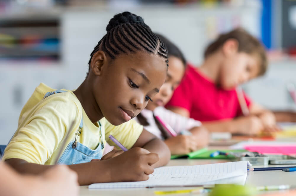 Students write at their desks in a classroom