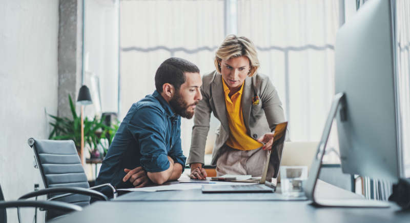 Two businesspeople read a laptop screen