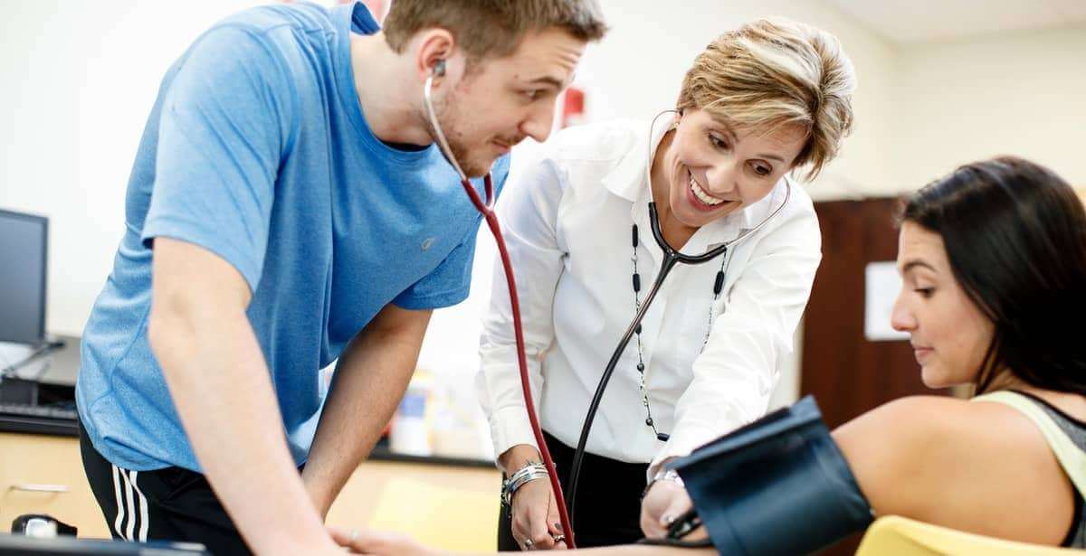Nurse leader teaching nursing student how to measure blood pressure